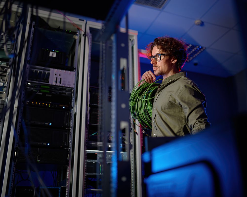 Telecom engineer in data center reviewing fiber optic infrastructure