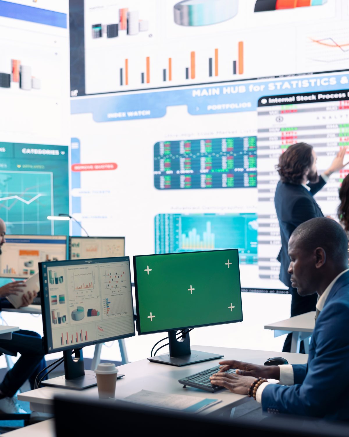 Financial services analyst at multi-monitor workstation reviewing trading dashboards