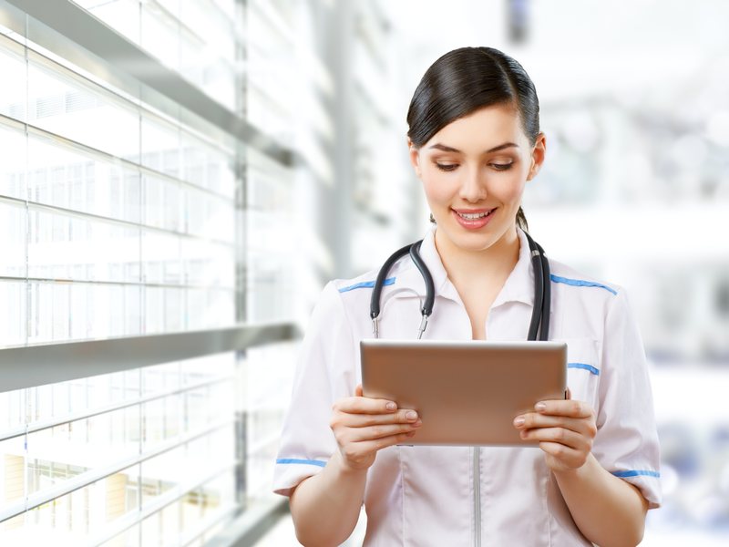 Healthcare professional reviewing patient data on a tablet — HIPAA / HITRUST / FDA-compliant staffing